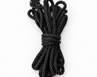May include: A coil of thick black rope made of twisted fibres, neatly bundled and secured with a central wrap. The rope features a textured, multi-strand construction with frayed ends visible at the top, showcasing a consistent dark colour.