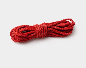 May include: A length of tightly coiled, bright red rope. The rope is a solid, vibrant colour and appears to be made of a durable, woven material. The image is a close-up shot against a plain white background.