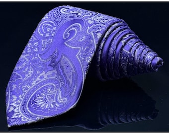 May include: A rolled-up purple paisley tie with a detailed white pattern. The tie is made of a shiny fabric and is displayed on a dark reflective surface. The intricate design and color make it a stylish accessory.
