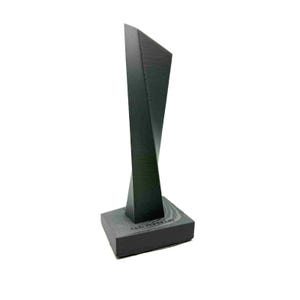 May include: A dark gray, abstract sculpture with a twisted design. The sculpture is mounted on a rectangular base with the text "LED ZEPPELIN" engraved on it. The artwork has a modern, minimalist aesthetic.