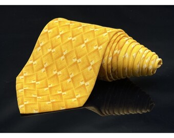 May include: A rolled-up yellow tie with a repeating geometric pattern in a lighter shade of yellow. The tie is made of a shiny fabric and is displayed against a black background. The pattern consists of squares and rectangles.