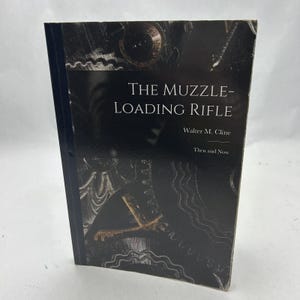 Puede incluir: Un libro de tapa dura titulado "The Muzzle-Loading Rifle" de Walter M. Cline. El libro tiene una cubierta oscura con ilustraciones de engranajes y otros elementos mecánicos. El lomo es azul oscuro.