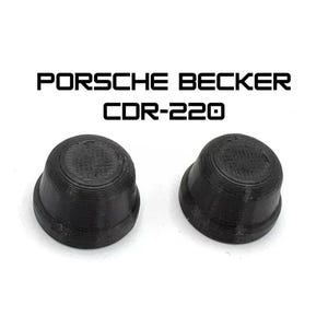 May include: Two black, rounded, plastic components with a ridged design. The text "PORSCHE BECKER CDR-220" is printed above the components in a bold, sans-serif font. The items are set against a white background.