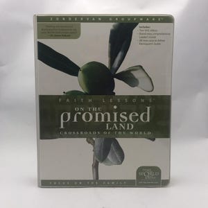 May include: A white and green book cover with the title "Faith Lessons on the Promised Land: Crossroads of the World" and the text "Focus on the Family". The cover features a green branch with leaves and olives.