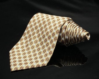 May include: A rolled-up necktie with a repeating floral pattern in tan, brown, and white. The tie is made of a shiny fabric and is displayed on a reflective black surface.