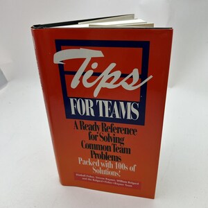 May include: A red book titled "Tips for Teams: A Ready Reference for Solving Common Team Problems Packed with 100s of Solutions!" by Kindell Fisher, Steven Reynet, William Belgard and the Belgard-Fisher-Rayner Team.