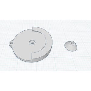 Puede incluir: Un objeto renderizado en 3D de color gris claro, que presenta una base circular con un recorte parcial y una pequeña pieza cónica. La base tiene un agujero central y una pequeña protuberancia circular. Los objetos están sobre un fondo de cuadrícula.