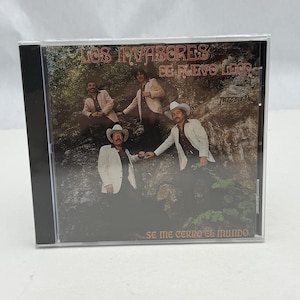 Op de afbeelding: Een CD-hoes met een foto van een band genaamd "Los Invasores de Nuevo Leon". De bandleden dragen witte pakken en staan voor een rotsachtige achtergrond. De albumtitel is "Se Me Cerro El Mundo".