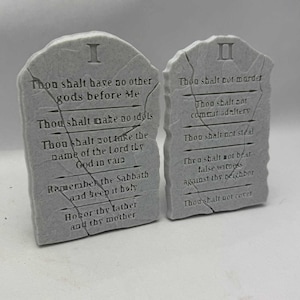 May include: Two gray stone tablets with the Ten Commandments inscribed in English. The tablets are rectangular with a rough, textured surface and a cracked appearance. The first tablet is labeled "I" and the second "II".