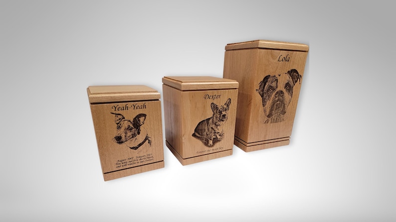 May include: Three wooden pet urns with engraved portraits of dogs and their names: "Lola", "Dexter", and "Yeah-Yeah".