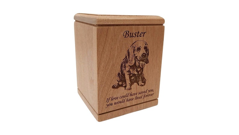 May include: A wooden pet urn with an engraved image of a dog and the name "Buster". The urn has the inscription "If love could have saved you, you would have lived forever".