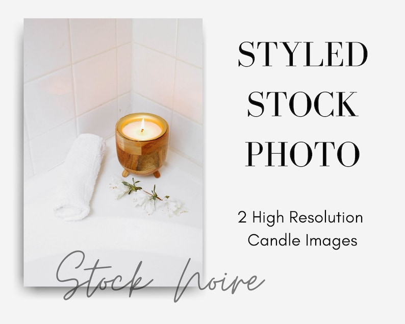 May include: A wooden candle holder with a lit candle inside, a white towel, and white flowers on a white tiled surface.