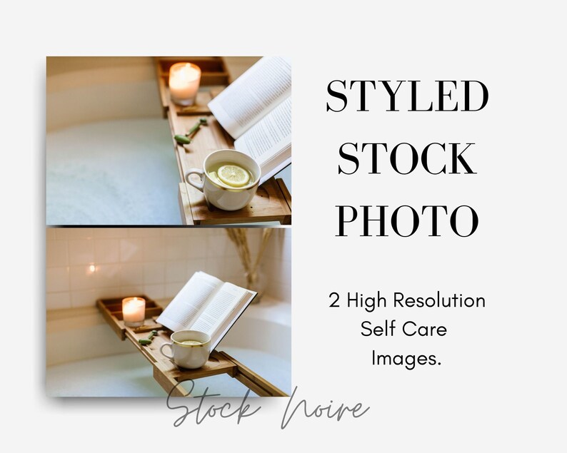 May include: A white bathtub with a wooden bath tray holding a book, a cup of tea with a lemon slice, and a lit candle. The bathtub is filled with water and bubbles.