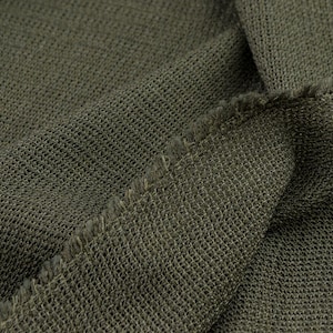 Peut inclure: Gros plan sur un tissu tricoté vert avec une couture visible. Le tissu a une apparence texturée et tissée.