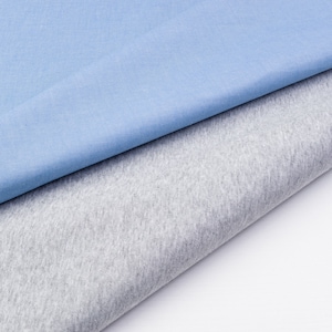 May include: A close-up of two fabric swatches. One is a light blue cotton fabric and the other is a gray cotton fabric.