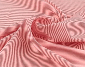 May include: Pink and white striped fabric with a soft, crinkled texture. The fabric is folded and draped, showing the pattern and texture.