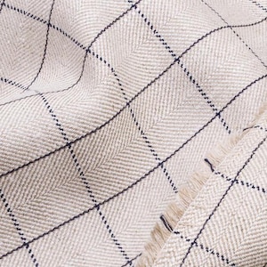 May include: Close-up of a beige fabric with a herringbone weave and a black and white checkered pattern.
