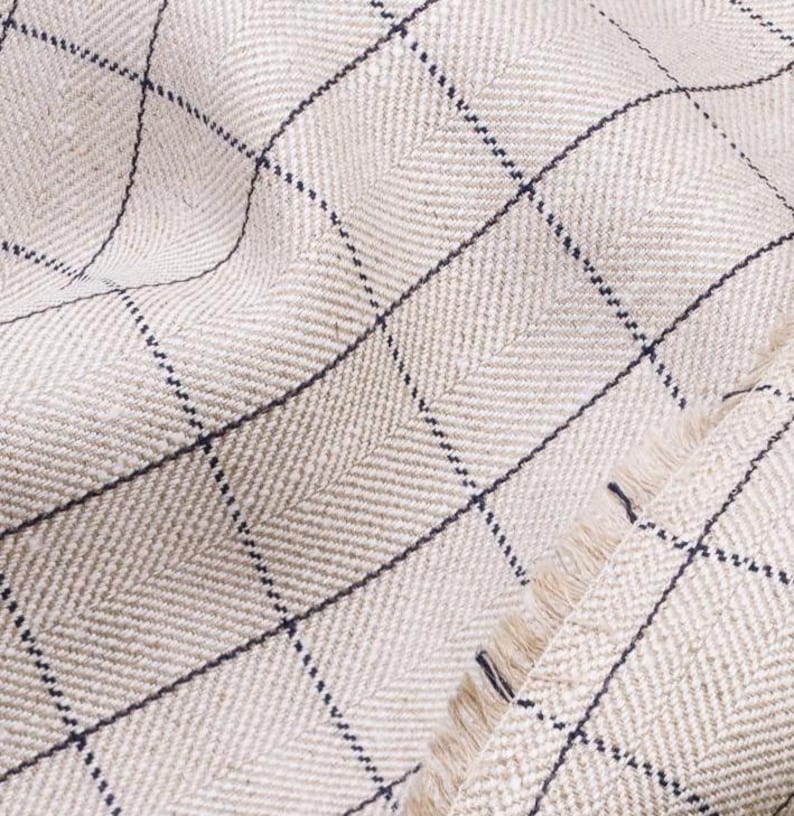 May include: Close-up of a beige fabric with a herringbone weave and a black and white checkered pattern.