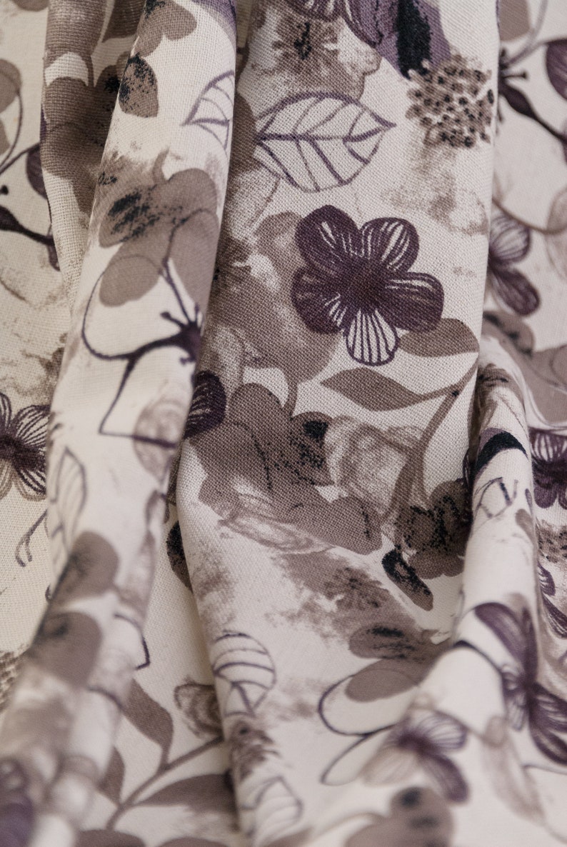 May include: A close-up of a white fabric with a brown floral pattern. The fabric is folded and the pattern is visible on both sides of the fold.