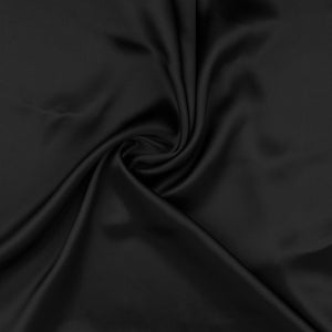 May include: A smooth, black fabric with a soft, flowing texture. The fabric is draped and folded, creating a luxurious and elegant look.