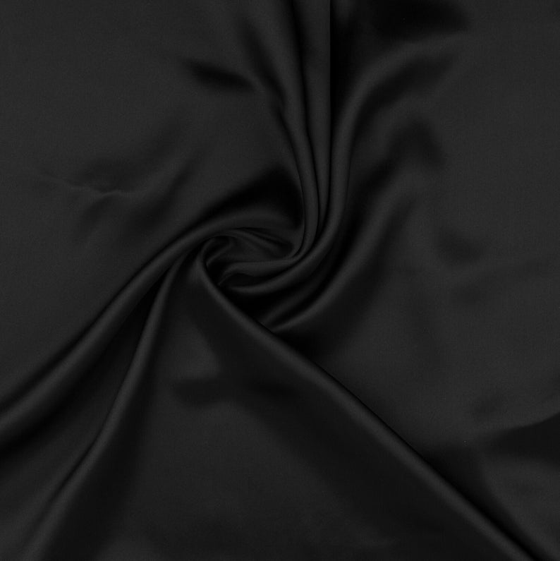 May include: A smooth, black fabric with a soft, flowing texture. The fabric is draped and folded, creating a luxurious and elegant look.