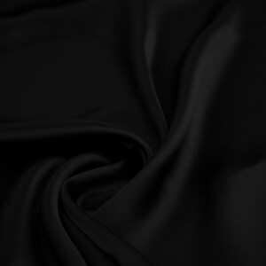 May include: Close-up of a smooth, black fabric with soft folds and wrinkles. The fabric has a luxurious, silky texture.