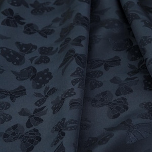 May include: Dark blue fabric with a repeating embossed pattern of butterflies and bows.