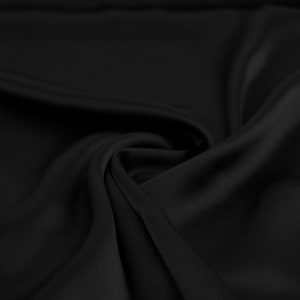 May include: Black fabric with smooth, silky texture, draped and folded to create soft curves and folds.