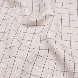 May include: A close-up of a beige fabric with a black and white checkered pattern. The fabric is wrinkled and has a soft, textured appearance.