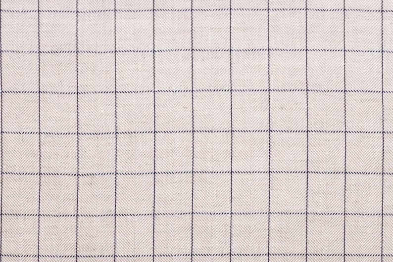 May include: A close-up of a beige fabric with a fine, dark blue grid pattern. The fabric has a subtle herringbone weave.