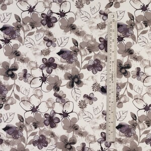 May include: White fabric with a repeating pattern of brown and purple flowers and leaves. A ruler is visible on the right side of the image.