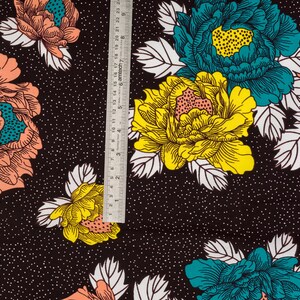 May include: Black fabric with a white polka dot pattern and a repeating floral design. The flowers are in shades of pink, yellow, and teal.