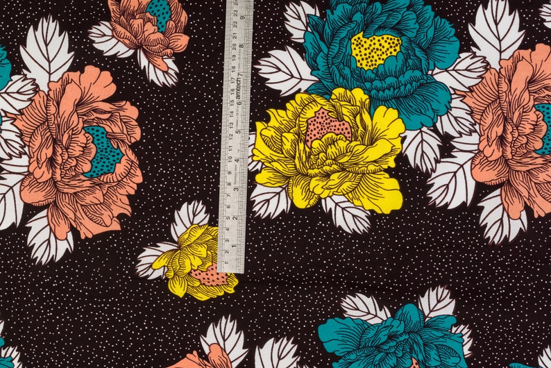 May include: Black fabric with a white polka dot pattern and a repeating floral design. The flowers are in shades of pink, yellow, and teal.