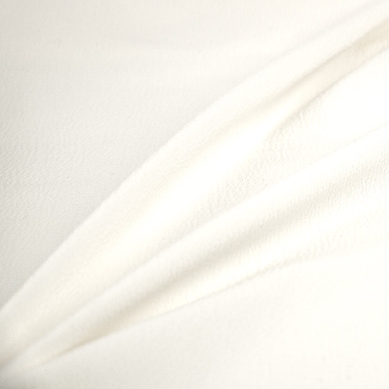 May include: White fabric with a smooth, soft texture. The fabric is folded and draped, creating a gentle curve.