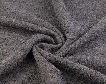Op de afbeelding: Close-up van een donkergrijze, textuurrijke stof met een zacht, pluche oppervlak. De stof is gevouwen en gedrapeerd, waardoor de textuur en de drape zichtbaar zijn.