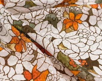 May include: White fabric with a brown and orange floral pattern. The fabric is sheer and has a textured surface.
