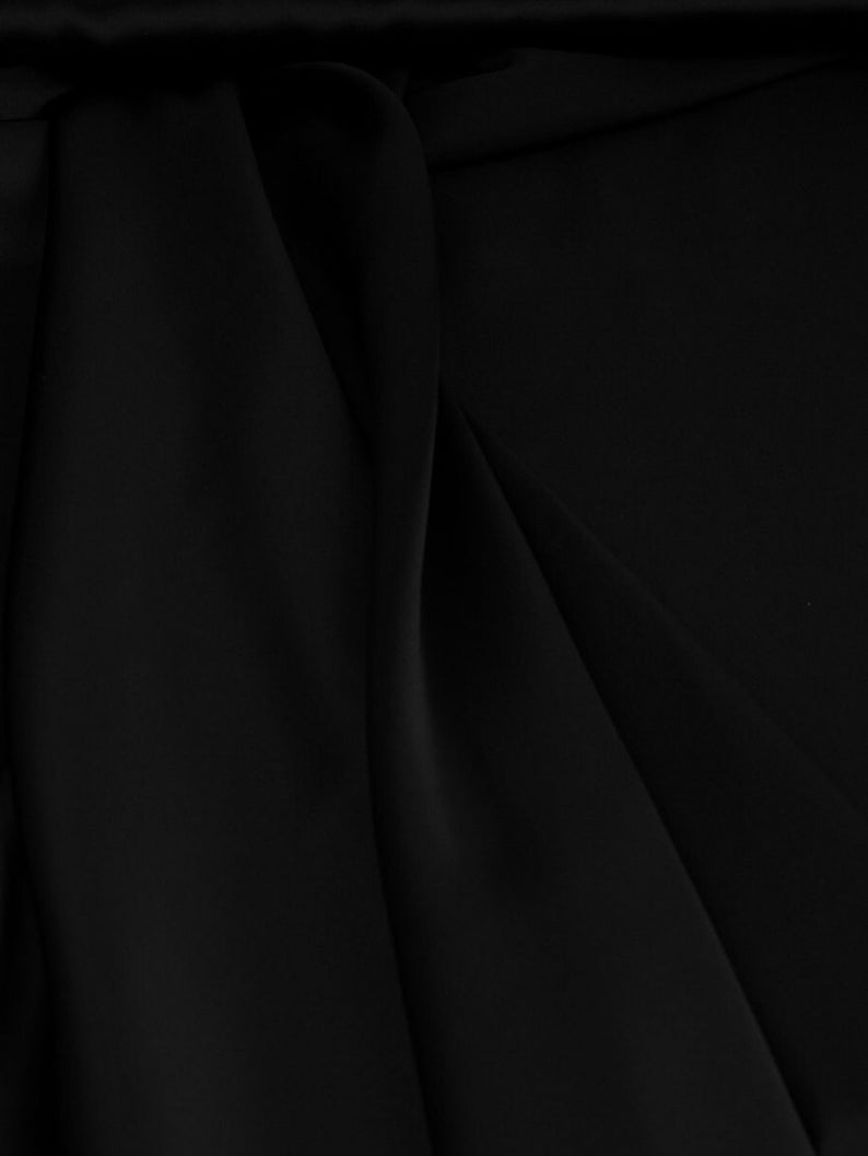 May include: Black fabric with smooth, flowing folds. The fabric has a soft, luxurious feel.
