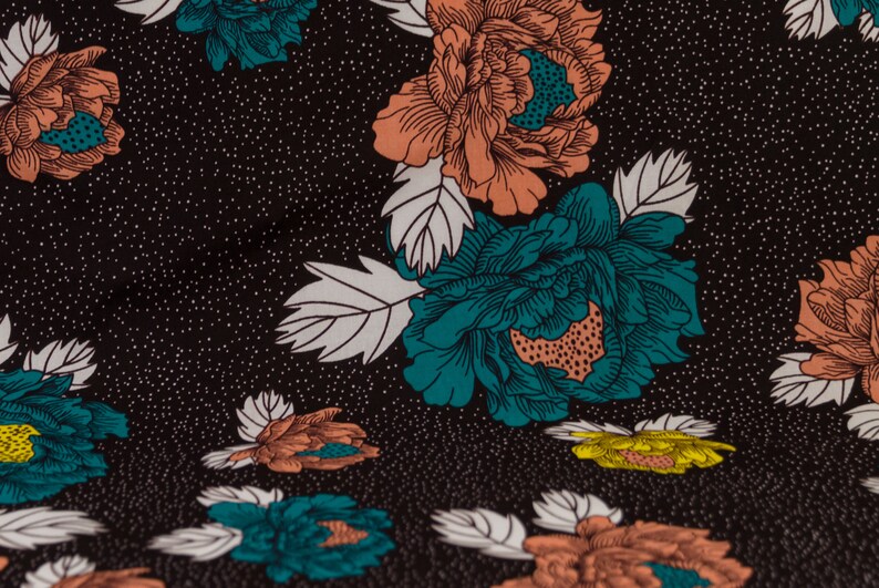 May include: Black fabric with a repeating pattern of teal and peach flowers with white leaves. The background is a dark black with a subtle white speckled pattern.