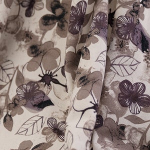 May include: A beige fabric with a brown floral pattern. The fabric is folded and the pattern is visible on both sides of the fold.