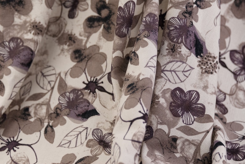 May include: A beige fabric with a brown floral pattern. The fabric is folded and the pattern is visible on both sides of the fold.