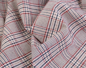 May include: Close-up of a fabric with a red, black, and white plaid pattern.