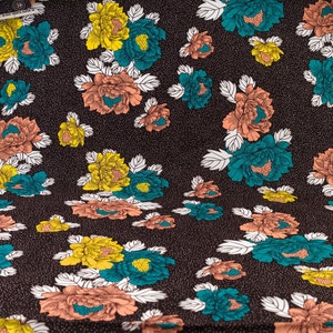 May include: A brown fabric with a repeating pattern of teal, yellow, and peach flowers. The flowers have white outlines and are set against a dark brown background with a subtle white speckled pattern.