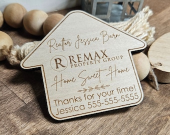 May include: A wooden house-shaped sign with the text "Realtor Jessica Barr" and "RE/MAX PROPERTY GROUP" in a circle with the letter "R" inside. The sign also says "Home Sweet Home" with a floral design and "Thanks for your time! Jessica 555-555-5555".