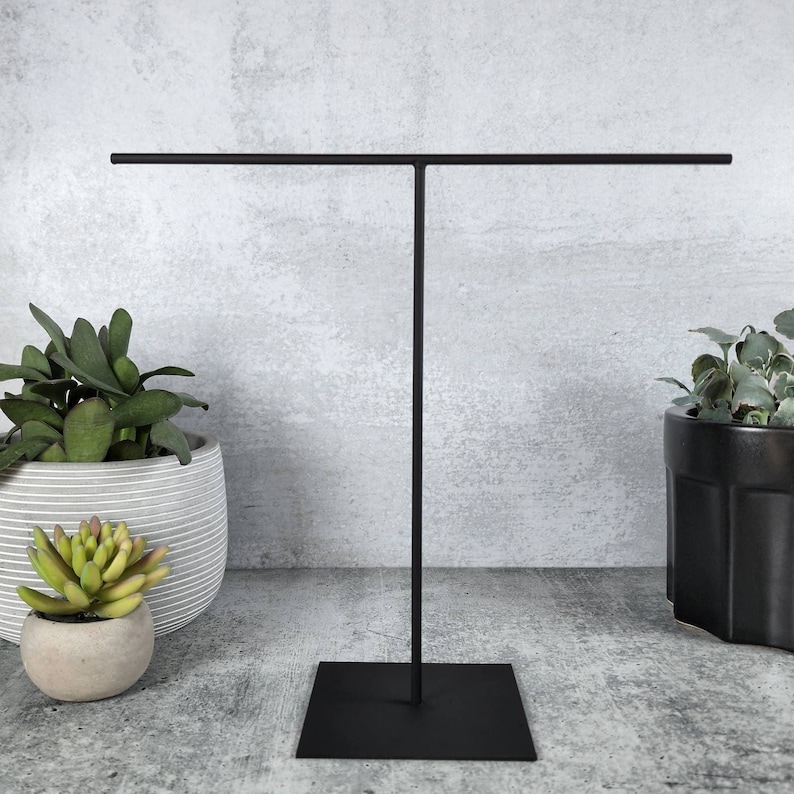 Modern metal necklace display stand, designed with a sleek and minimalist aesthetic. It effortlessly holds up to 20 dainty necklaces, showcasing them in a clean, organized manner.