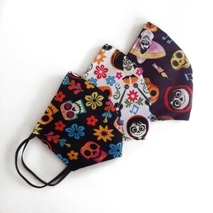 May include: Three colorful face masks with a Day of the Dead theme. The masks feature floral patterns, skeletons, and characters from the movie Coco.