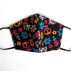 May include: Black face mask with a colorful Day of the Dead pattern featuring sugar skulls, flowers, and leaves.
