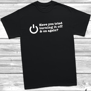 May include: Black t-shirt featuring a white power button symbol and the phrase "Have you tried turning it off & on again?" in white. The shirt is made of a soft material and has short sleeves.