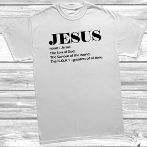 May include: White t-shirt featuring the word "JESUS" in black, bold font. Underneath, definitions are provided: "noun / Je'sus", "The Son of God.", "The Saviour of the world.", and "The G.O.A.T - greatest of all time."