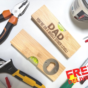 May include: A wooden level and bottle opener combo with the word "DAD" and the phrase "YOU'RE ON A WHOLE OTHER LEVEL!" engraved on it. The image also shows pliers, a wrench, screws, and a can of paint.