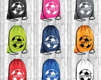 Op de afbeelding: Negen trekkoordtassen met een voetbalontwerp en gepersonaliseerde namen. De tassen zijn in verschillende kleuren verkrijgbaar, waaronder zwart, roze, grijs, groen, blauw, oranje, rood, wit en lichtblauw.